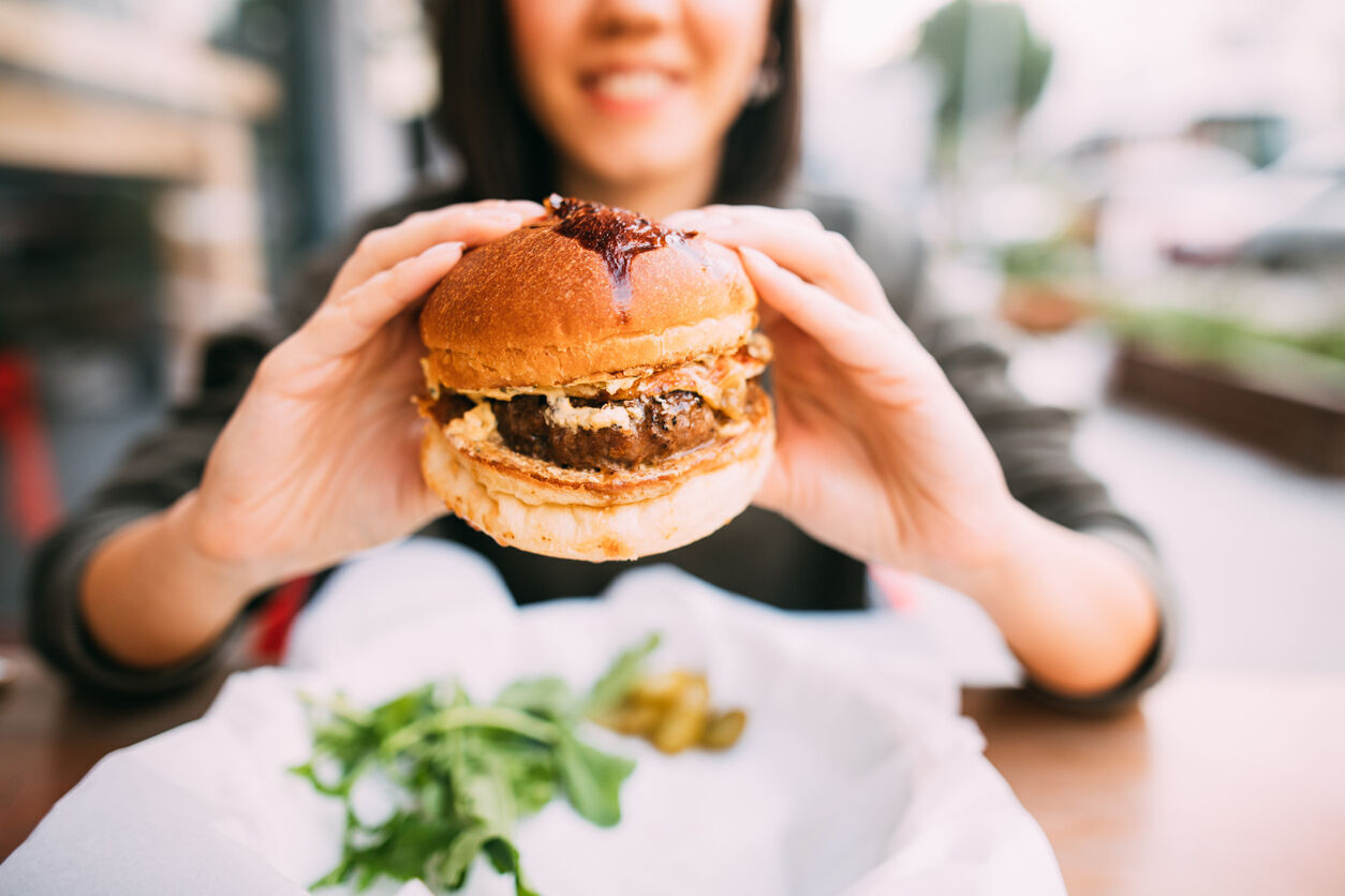 Woman eating beef burger (Photo) Credit agrobacter (iStock)
